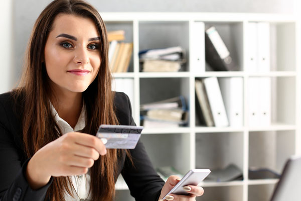 Woman holding credit card about to purchase using mobile phone.