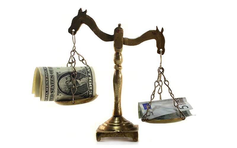 Balancing scale with US Dollars and Canadian Dollars.