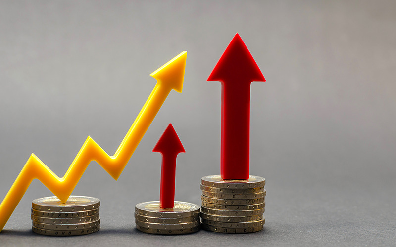 Image of a line chart trending upwards above some coins.