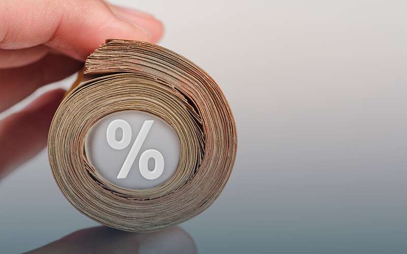 A rolled-up wad of cash with a percentage sign in the middle of the money representing rates and pricing models.